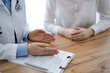 © rogerphoto - Doctor and patient discussing something while sitting near each other at the wooden desk in clinic, view from above. Medicine concept