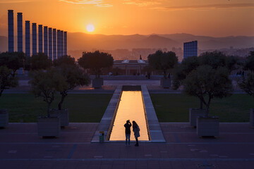 Dos personas a contraluz fotografían el atardecer en el paisaje urbano de Barcelona