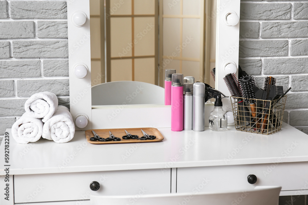 Different hair sprays and accessories on table in beauty salon