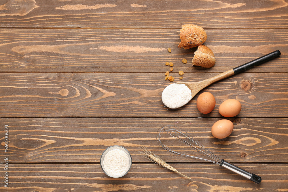Composition with wheat flour, eggs, bread and utensils on wooden table