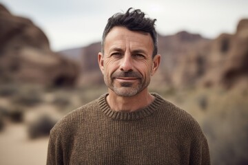 Wall Mural - Environmental portrait photography of a pleased man in his 40s wearing a cozy sweater against a canyon or desert landscape background. Generative AI