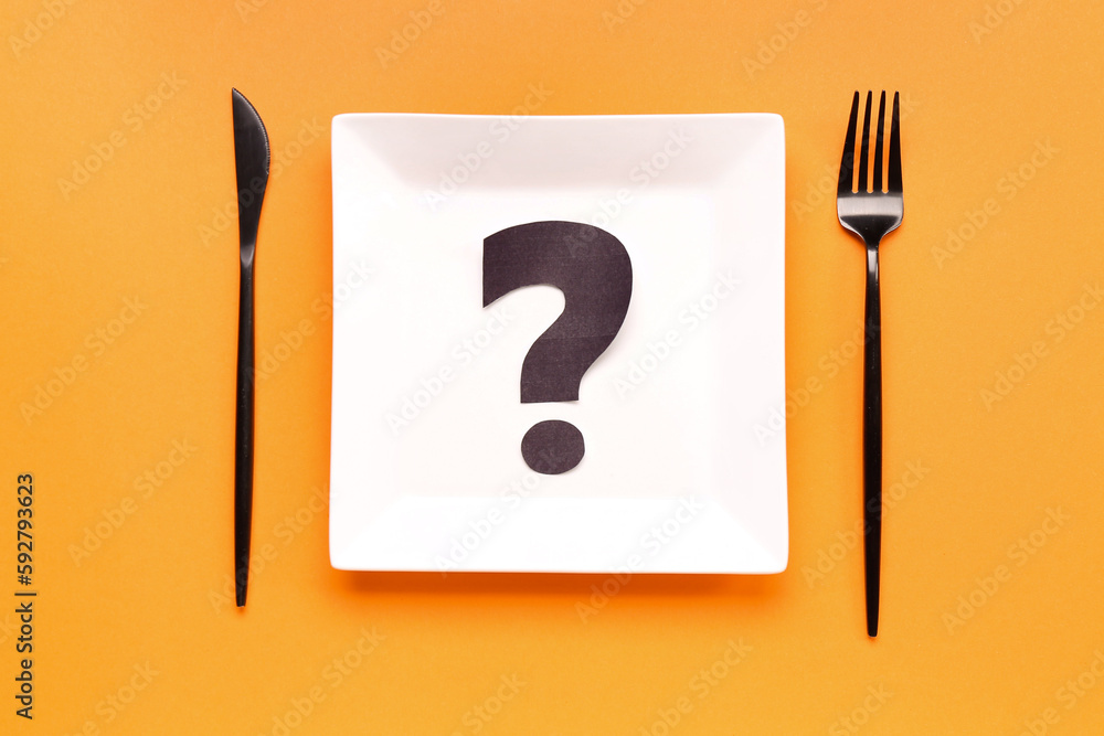 Plate with question mark and cutlery on orange background