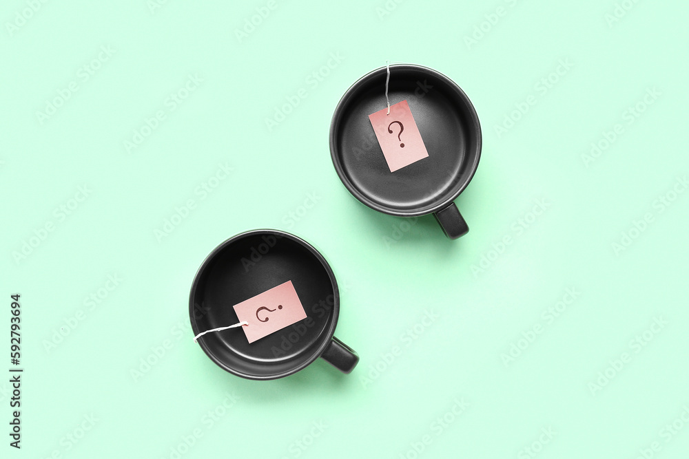 Cups with paper question marks on green background