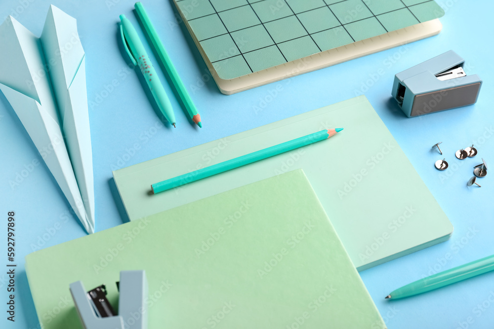 Composition with stationery supplies and paper plane on blue background