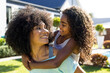 © Wavebreak Media - Happy biracial mother carrying her daughter and smiling to her in garden on sunny day