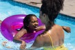 © Wavebreak Media - Happy biracial mother and daughter playing with inflatable in sunny outdoor swimming pool