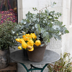 Wall Mural - A bouquet of yellow ranunculus and eucalyptus branches on a glass table at the entrance to the store