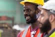 © eakgrungenerd - Close up engineering male african american happy smiling workers wear yellow helmet standing at factory industrial.