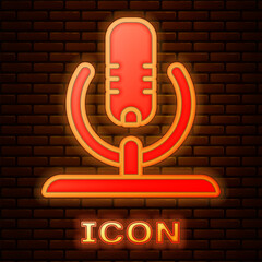 Sticker - Glowing neon Microphone icon isolated on brick wall background. On air radio mic microphone. Speaker sign. Vector