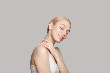 Wall Mural - Cute woman with blonde ponytail smiling isolated on grey background. Beauty,cosmetics, skincare, glamour.