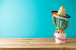 Mexican table decoration with cactus and sombrero hat  over blue background. Cinco de Mayo holiday celebration