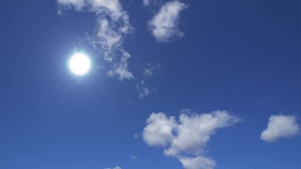 Wall Mural - Sun and clouds. Bright midday sunshine in blue sky with moving clouds. Seamless loop, time lapse