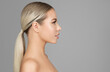 © inarik - Beautiful Young Woman Face Profile. Beauty Girl with Blond Pony Tail Hairstyle Side view over Gray. Woman Facial and Neck Skin Care. Women Plastic Surgery and Spa Treatment