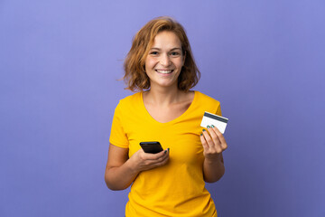 Young Georgian woman isolated on purple background buying with the mobile with a credit card