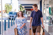 © Austockphoto - Man providing support to go shopping in town for person with a disability walking and talking