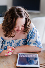 Smiling Young Person With Down Syndrome Using Ipad Technology Typing