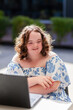© Austockphoto - Portrait of young lady with a disability looking to the side sitting with laptop