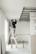 The Worker Attaches Plasterboard On Metal Frame. Installation Of Ceiling