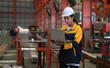 © Nassorn - Female industrial engineer in white helmet and safety jacket work in heavy metal engineering factory. Latin technician woman worker using laptop computer in metalwork manufacturing facility, portrait.