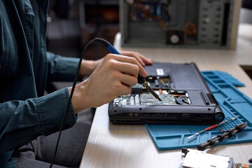 Wall Mural - Cropped unrecognizable man disassembles broken laptop. Computer service and repair concept. Laptop disassembling in repair shop, workshop. Electronic development by professional technician