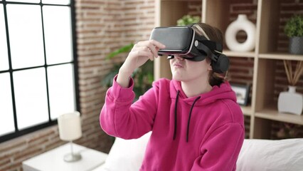 Poster - Young blonde woman playing video game using virtual reality glasses at bedroom