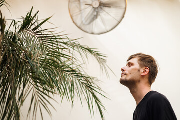 Fototapete - Heat wave during a summer, a man finds respite at his home balcony with the help of an electric fan. A man beats the summer heat wave by finding relief with an fan. The effect of global warming