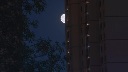 Wall Mural - Time lapse video of a bright moon in the sky at night covered by clouds