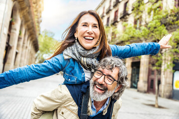 Happy senior couple having fun walking on city street - Two older tourists enjoying together weekend summer vacation - Life style, tourism and romantic moments concept