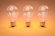 three retro style lightbulbs with glowing filament standing in a row on infinite colorful orange background; creativity design concept; 3D Illustration