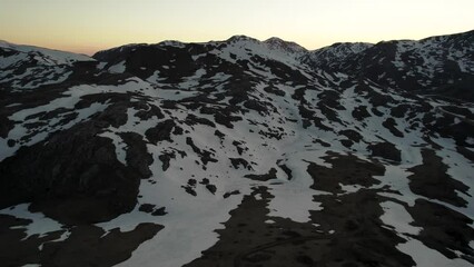 Sticker - Gorgeous aerial view of tall snowy mountains in the wilderness under a clear yellow sky