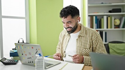 Sticker - Young hispanic man student listening to music using pen as a drummer at library university