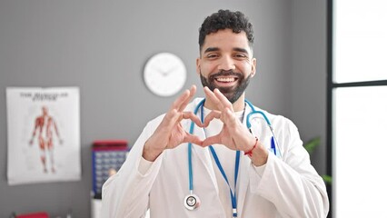 Sticker - Young hispanic man doctor smiling doing heart gesture with hands at clinic