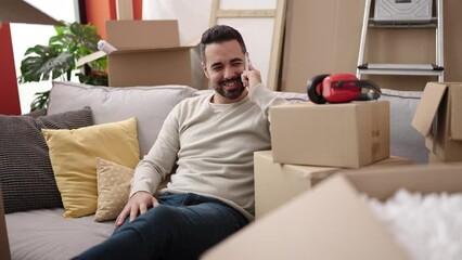 Sticker - Young hispanic man smiling confident talking on smartphone at new home