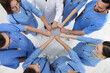 © New Africa - Doctor and interns holding fists together indoors, top view