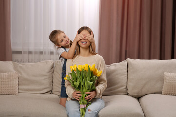 Sticker - Little daughter congratulating mom with bouquet of yellow tulips at home. Happy Mother's Day