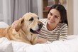 © New Africa - Happy woman with cute Labrador Retriever on bed at home