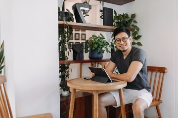 Wall Mural - Happy freelance asian man working in the cafe with his tablet.