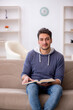 © Elnur - Young male student reading book at home