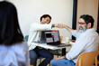 © Cavan Images - Happy male entrepreneurs giving fist bump while sitting in cafe