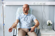Portrait of adult man sitting in comfortable chair with IV drip during treatment session in clinic