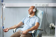© Seventyfour - Side view portrait of adult man wearing headphones and listening to music during IV drip treatment in clinic