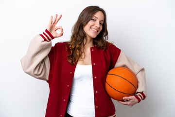 Wall Mural - Young caucasian woman playing basketball isolated on white background showing ok sign with fingers