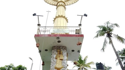 Wall Mural - Low angle of the golden Jesus Christ Blessing Statue on a pillar with icons surrounded by trees
