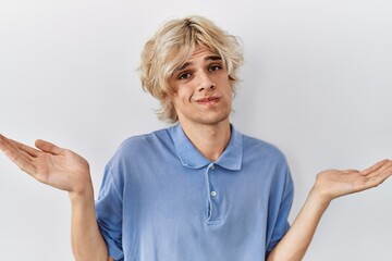 Sticker - Young modern man standing over isolated background clueless and confused expression with arms and hands raised. doubt concept.