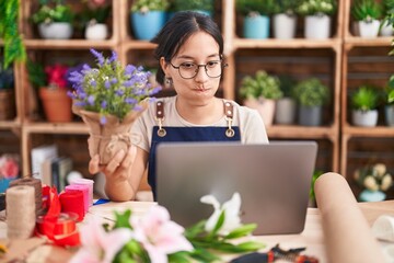 Canvas Print - Young hispanic woman working at florist shop doing video call puffing cheeks with funny face. mouth inflated with air, crazy expression.