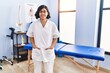 © Krakenimages.com - Young latin woman wearing physiotherapist uniform standing at physiotherapy clinic
