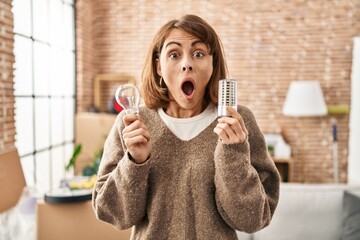 Canvas Print - Young beautiful woman holding led lightbulb and incandescent bulb afraid and shocked with surprise and amazed expression, fear and excited face.