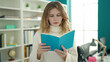 © Krakenimages.com - Young blonde woman student reading book standing at library university