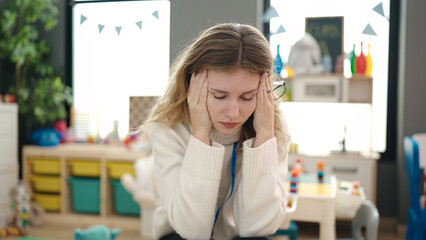 Sticker - Young blonde woman preschool teacher stressed sitting on chair at kindergarten