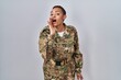 © Krakenimages.com - Beautiful african american woman wearing camouflage army uniform hand on mouth telling secret rumor, whispering malicious talk conversation